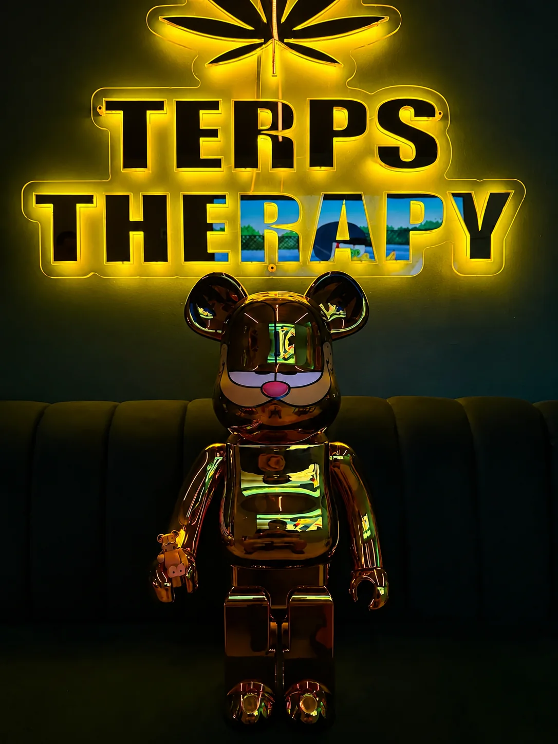Gold Bearbrick figure beneath the illuminated Terps Therapy sign inside the club