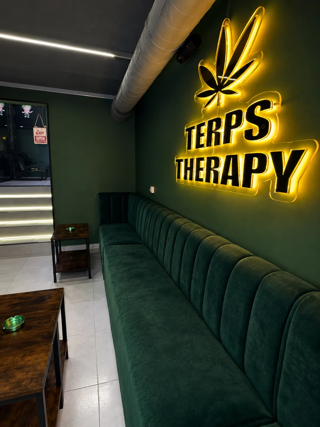 El Salon lounge at Terps Therapy with green velvet seating under a gold neon sign